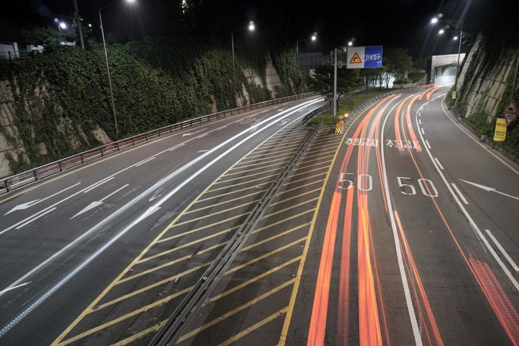 A  picture showing a Korean highway road with cars driving down