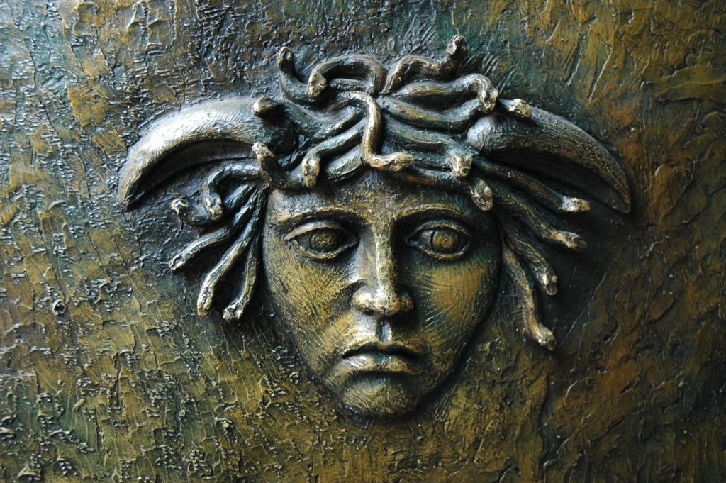 A stone statue of medusa that shows snakes in her hair.